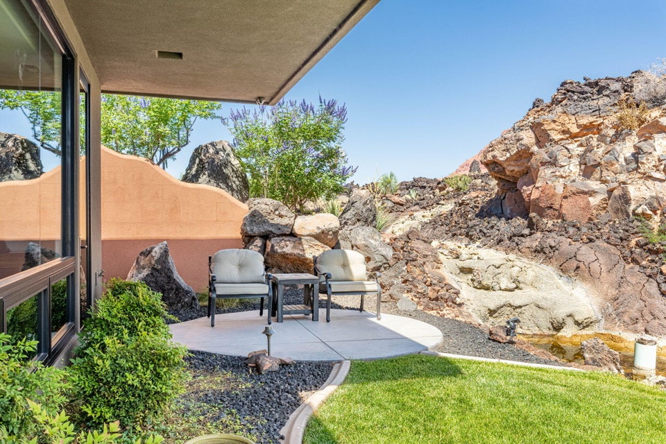 Circular concrete patio with black rock landscaping and integrated planting beds