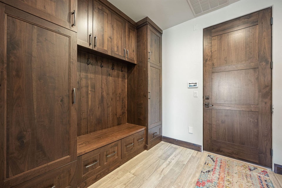 Built-in wood-finish cabinetry featuring storage, bench seating, and wall hooks