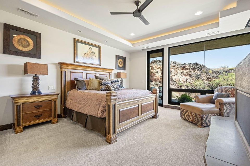 Spacious bedroom featuring large format window panels, recessed ceiling lighting, a contemporary ceiling fan, and a built-in stone fireplace hearth