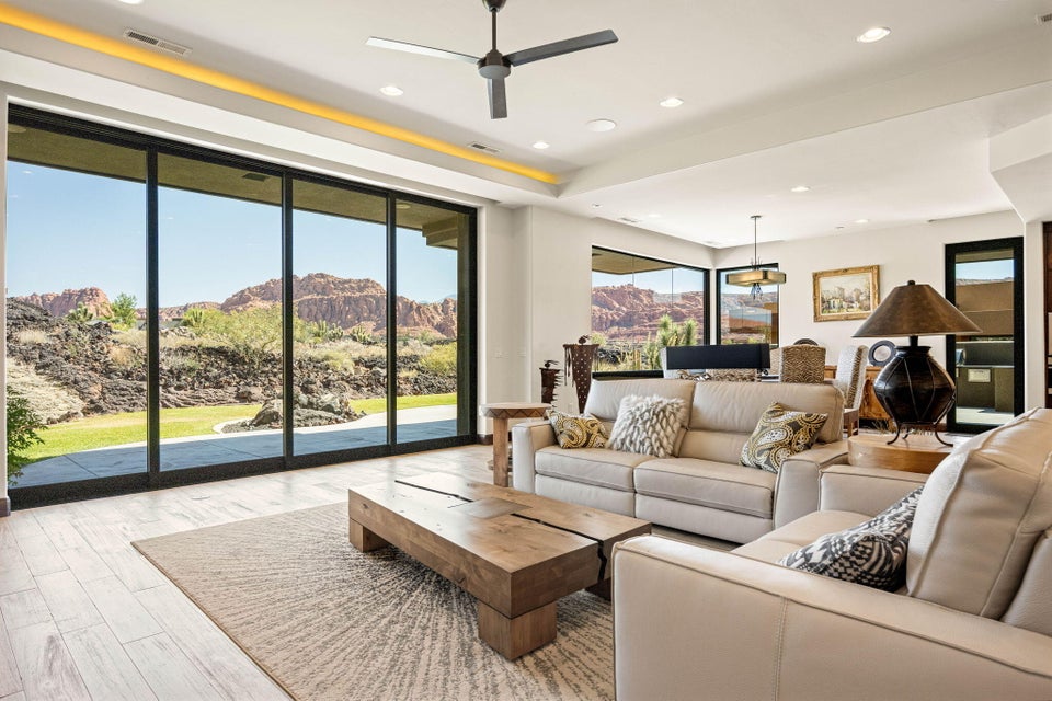 Spacious living area featuring expansive sliding glass doors, light-colored plank flooring, recessed ceiling lighting, and a contemporary ceiling fan