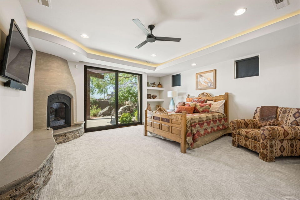 Spacious interior room featuring a plastered fireplace with a stone hearth, glass sliding doors, and carpeted flooring