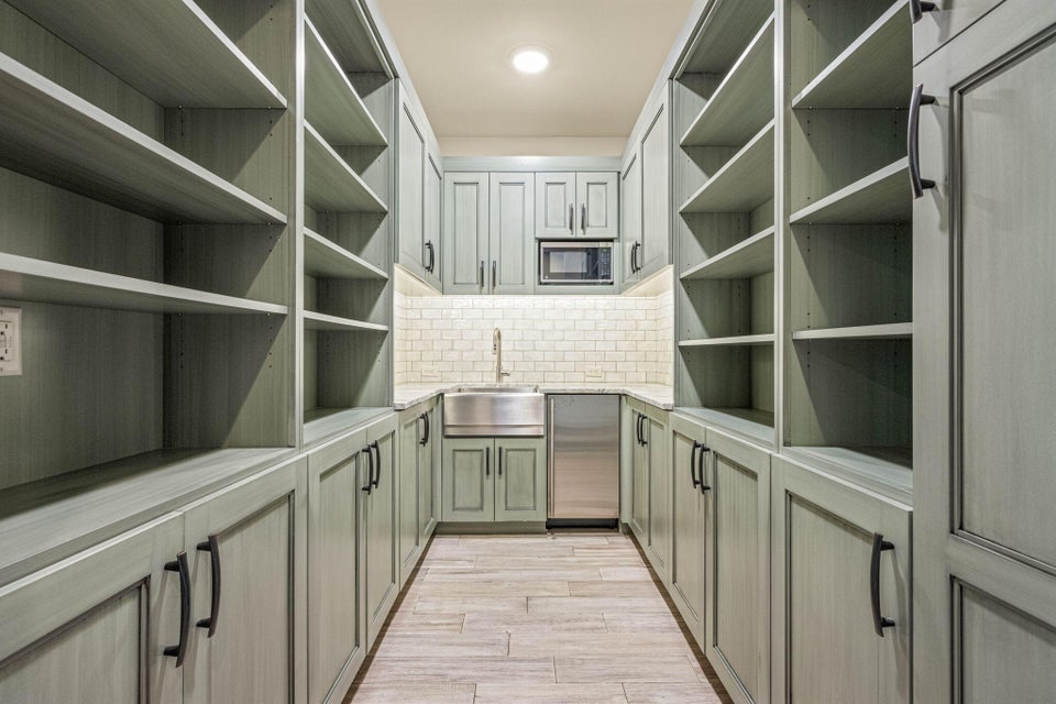 Dedicated pantry featuring extensive built-in shelving, lower cabinetry, and a full-size sink