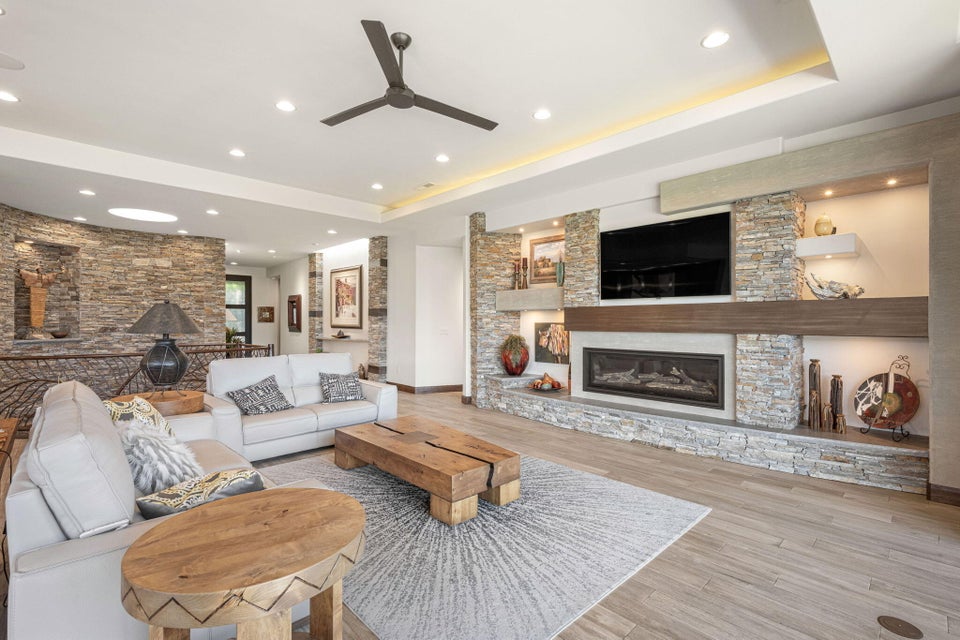 Living area with wood-finish flooring and a stone-clad fireplace featuring a wood mantle