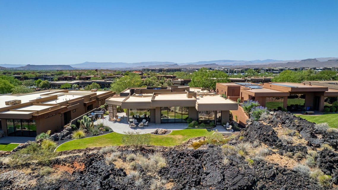 Modern architectural residence featuring a spacious patio, extensive glazing, and structured landscaping