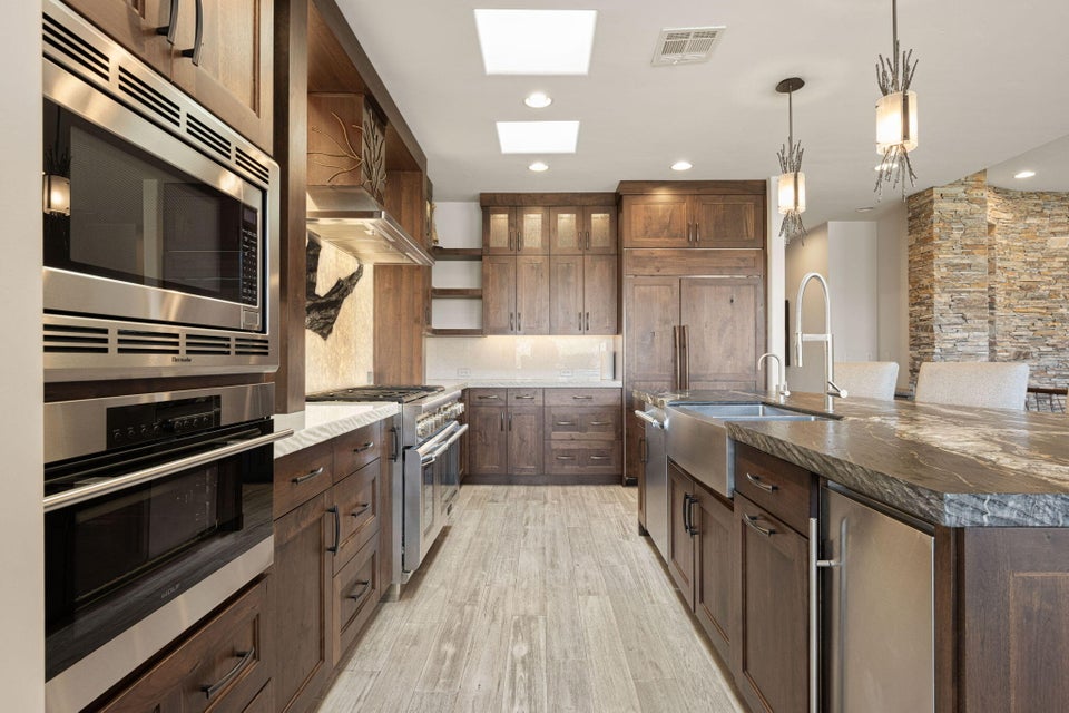 Gourmet kitchen featuring a built-in stainless steel microwave and oven, a stainless steel range with a ventilation hood, a farmhouse-style sink, and recessed lighting