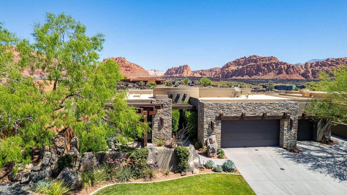 Stone-clad exterior featuring a prominent garage door, desert landscaping, and a manicured lawn