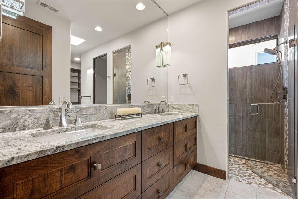 Double vanity with stone countertop, integrated sinks, and dark wood cabinetry