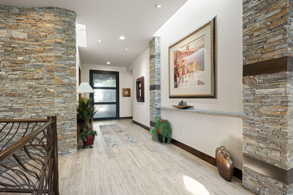 Hallway featuring stacked stone accent walls, recessed lighting, and wood-finish flooring