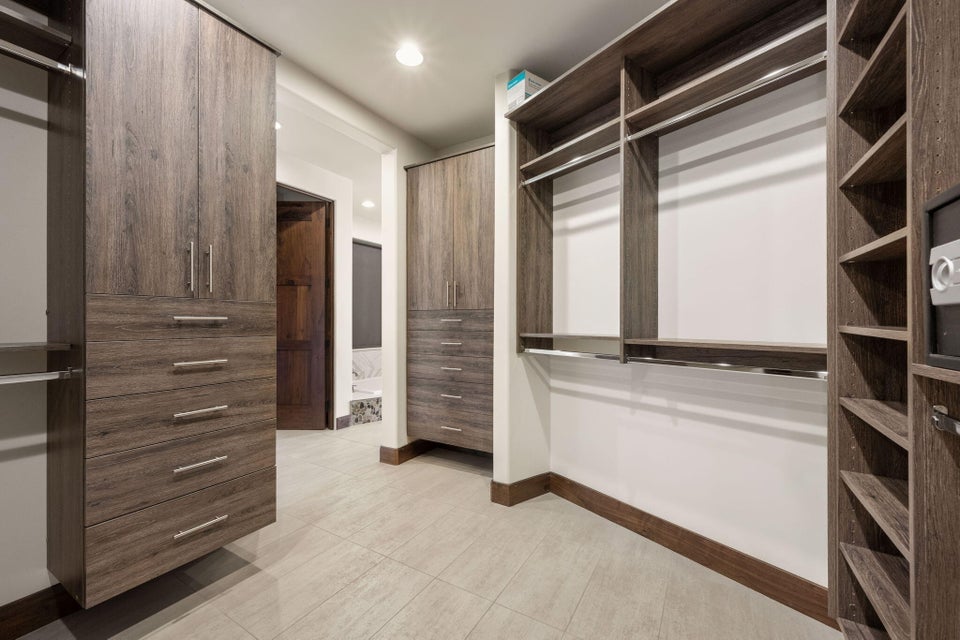 Custom closet system with wood-finish cabinetry, integrated drawers, shelving, and hanging rods