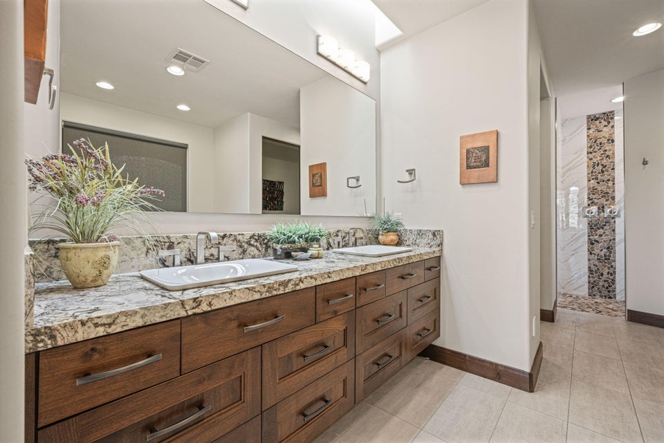 Dual vanity featuring wood-finish cabinetry, stone countertops, and rectangular undermount sinks