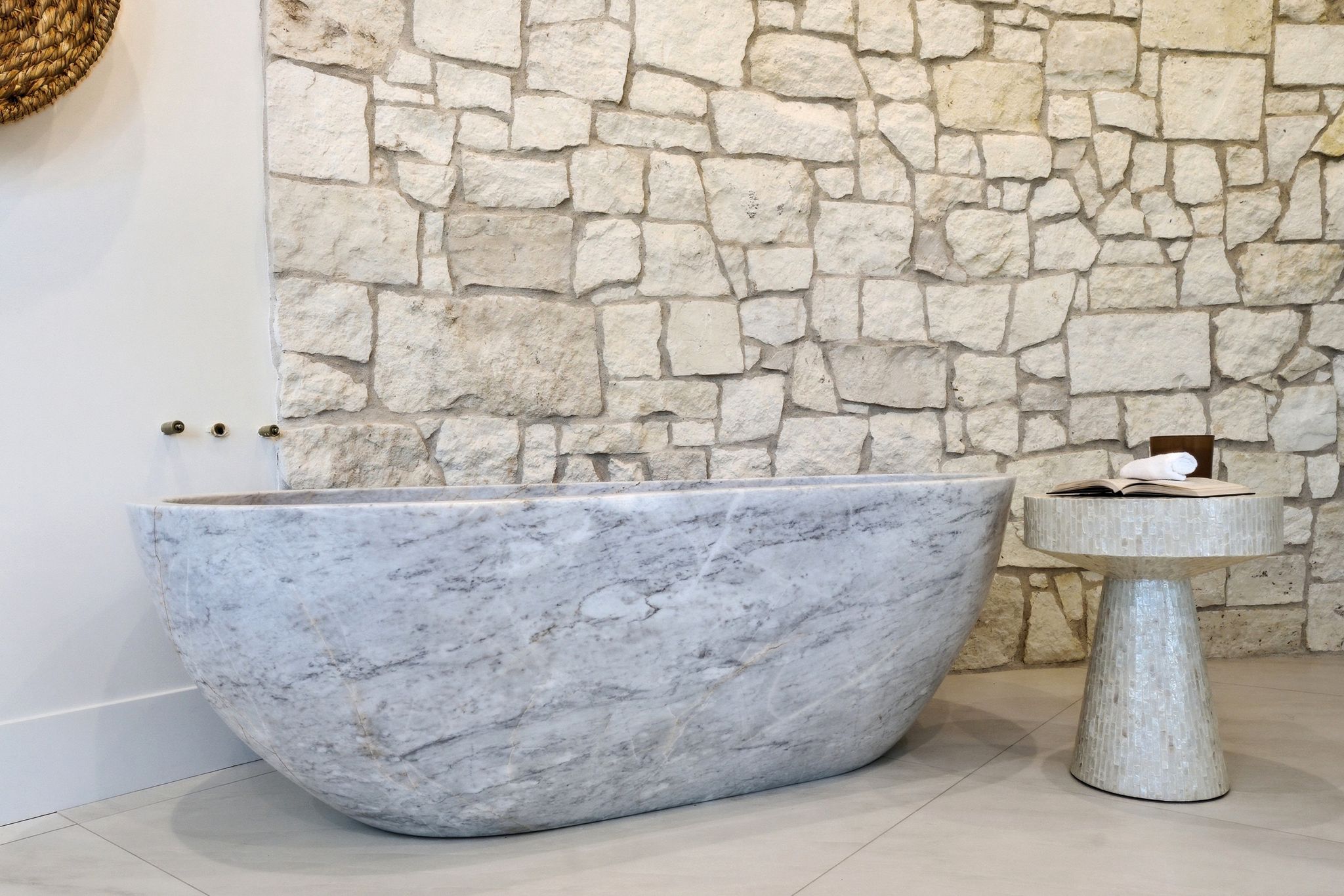 Freestanding stone bathtub with wall-mounted bronze fixtures