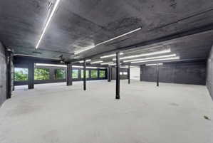 Spacious open room featuring a concrete floor, dark textured ceiling, and multiple linear ceiling lights