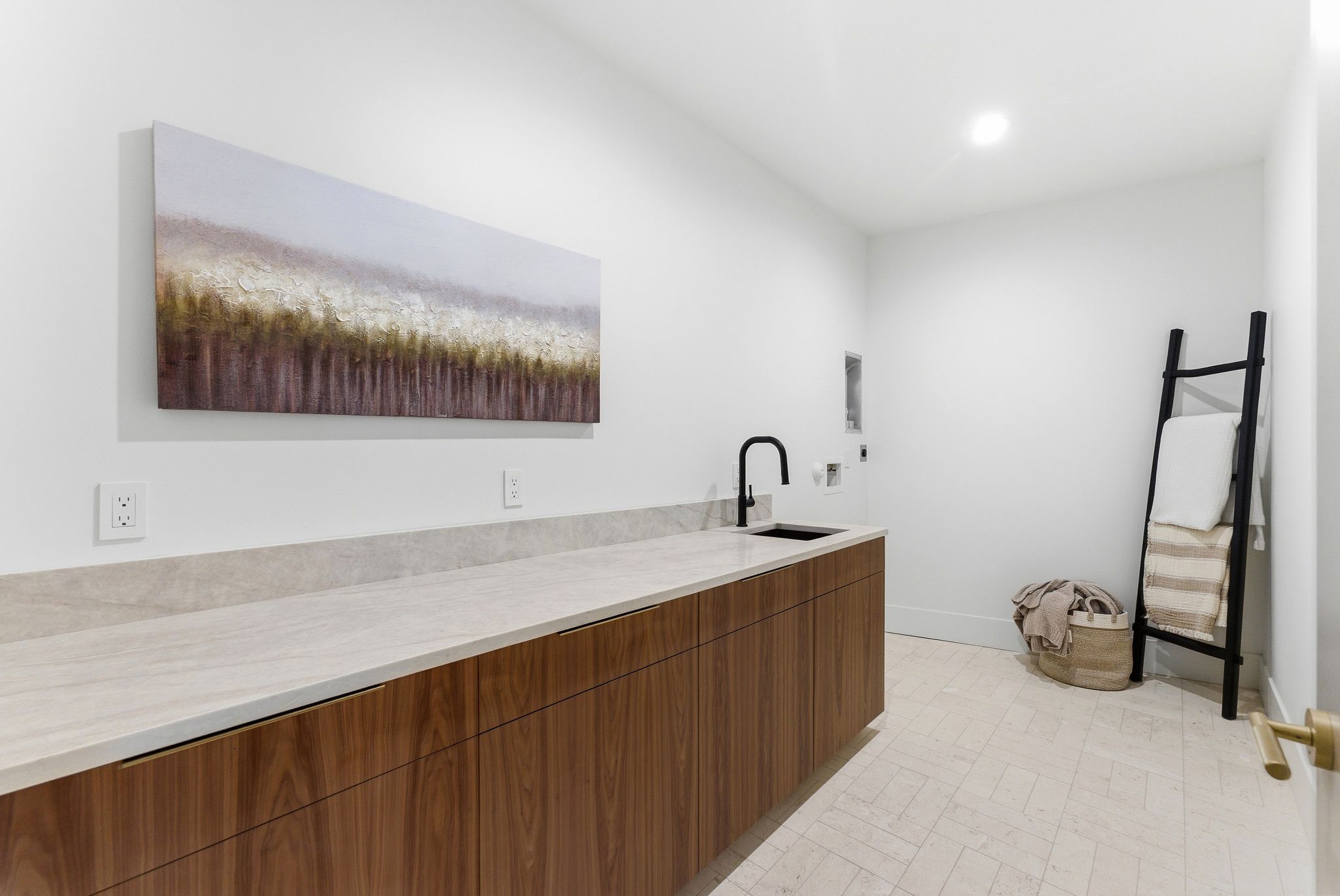 Utility room featuring an elongated countertop with an integrated sink, wood-finish cabinetry, and light-toned tile flooring