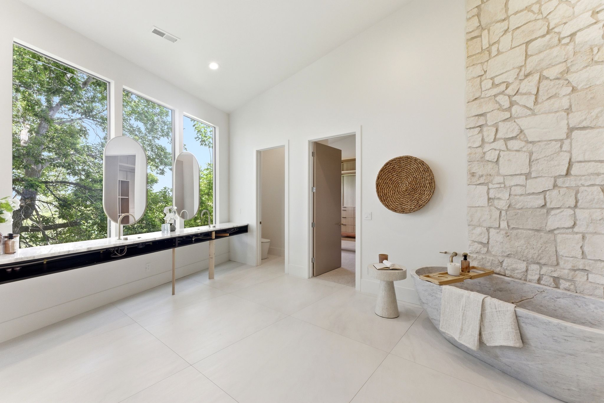 Freestanding natural stone soaking tub with a stone accent wall