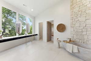 Freestanding natural stone soaking tub with a stone accent wall