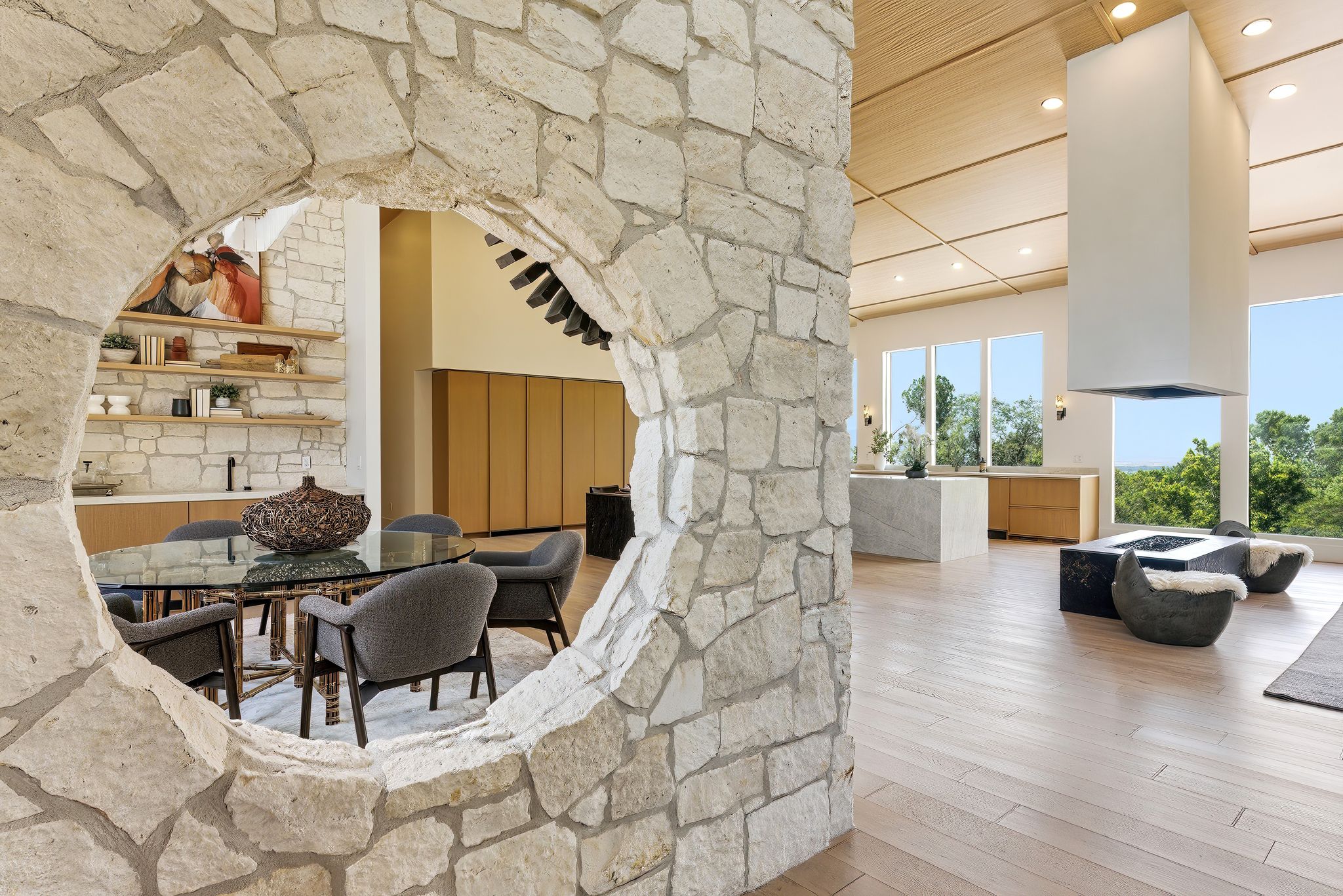Stone archway entry to a dining area featuring built-in shelving, a kitchen island with seating, and wood-finish flooring
