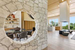 Stone archway entry to a dining area featuring built-in shelving, a kitchen island with seating, and wood-finish flooring