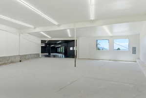 Spacious interior featuring a concrete floor, white walls, and exposed ceiling beams