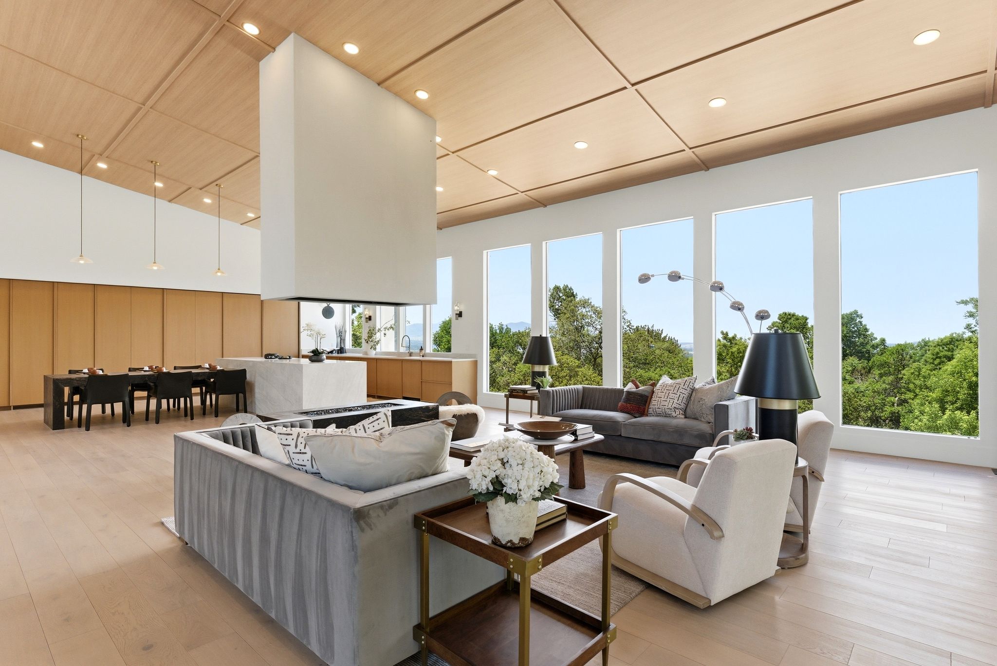 Open-concept living area featuring a central floating fireplace, wood-finish flooring, and a coffered wood ceiling