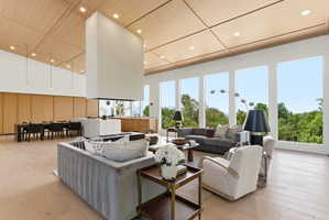 Open-concept living area featuring a central floating fireplace, wood-finish flooring, and a coffered wood ceiling