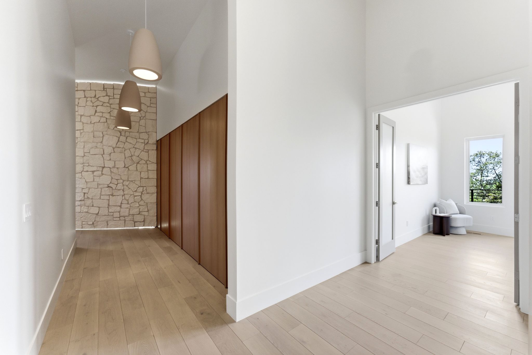 Bright hallway featuring wood-finish flooring, a stone accent wall, and integrated wood paneling