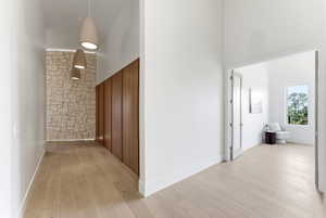 Bright hallway featuring wood-finish flooring, a stone accent wall, and integrated wood paneling