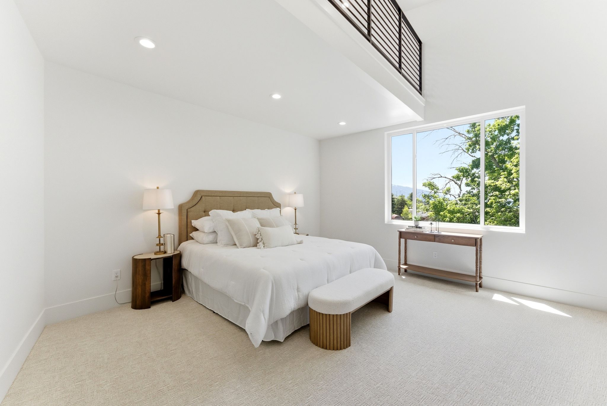 Bedroom featuring a large picture window, high ceilings, recessed lighting, neutral tone carpeting, and an overhead loft with a contemporary railing