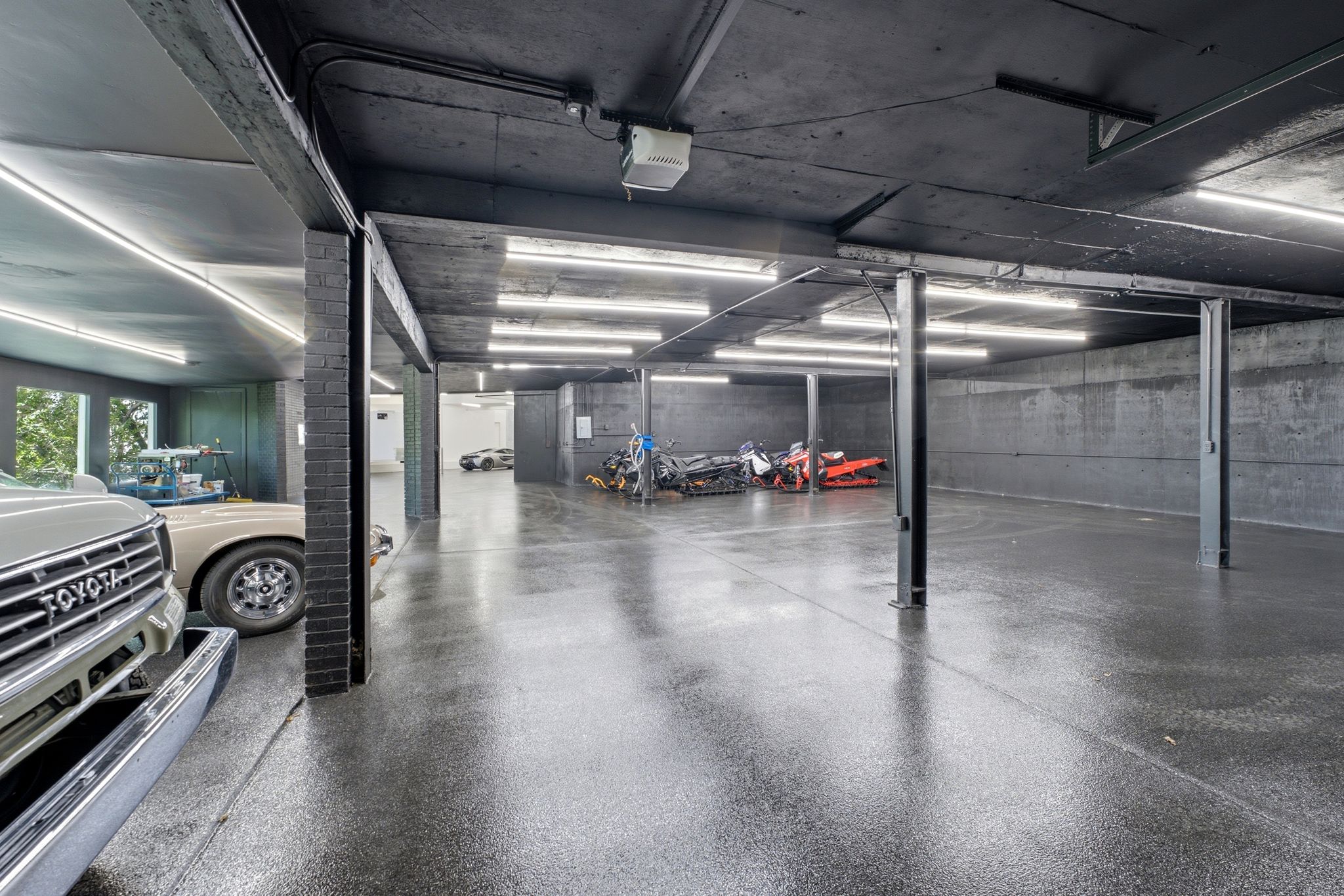 Spacious garage featuring a durable epoxy floor, exposed brick pillars, and ample fluorescent lighting