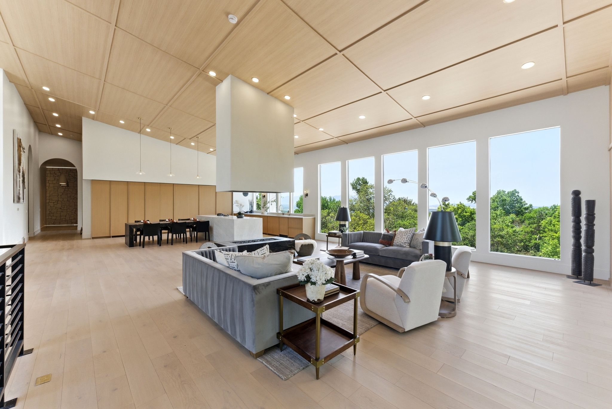 Expansive open-concept living space featuring high vaulted ceilings with wood paneling, numerous recessed light fixtures, and light wood-finish flooring