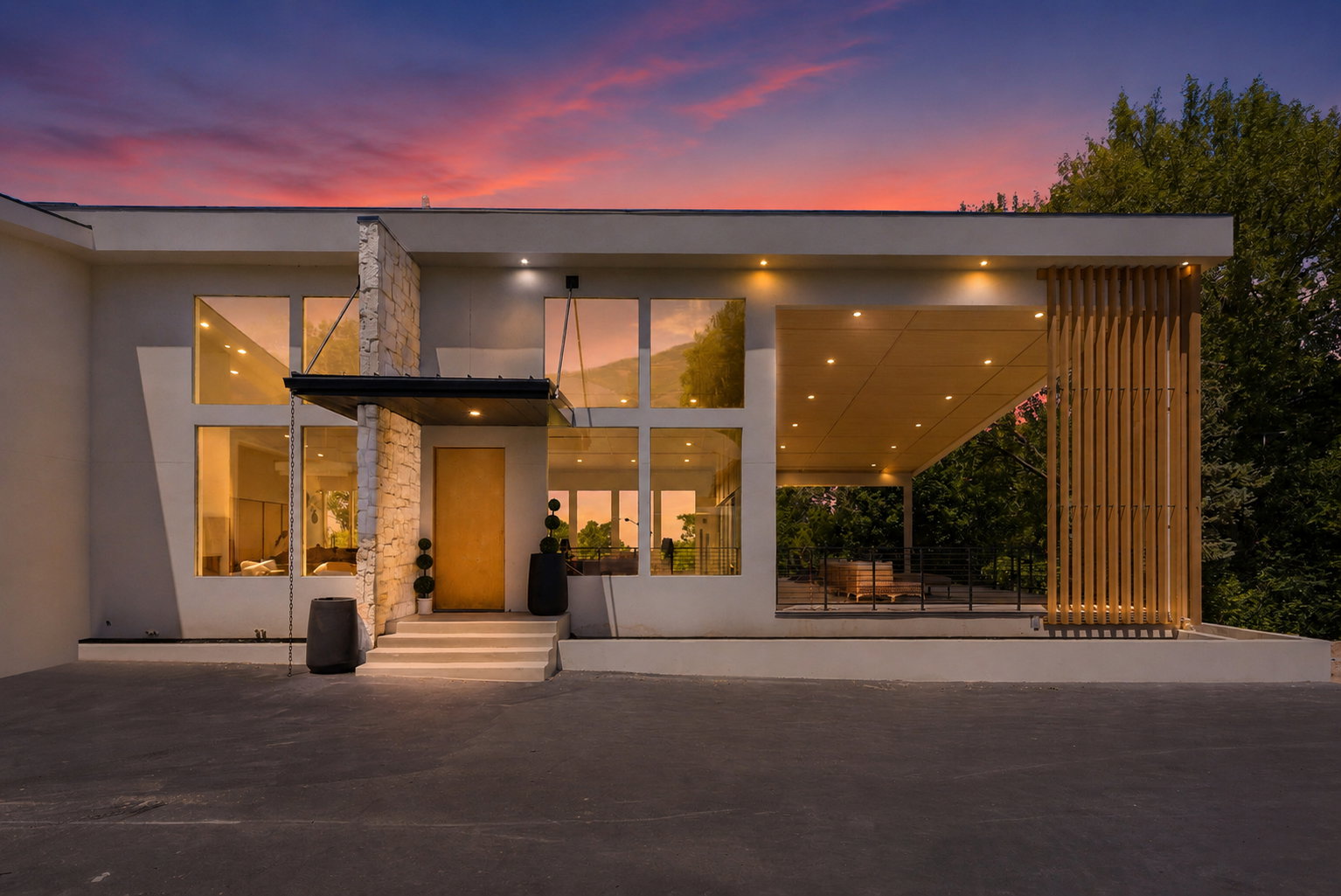 Modern architectural facade featuring large windows, stone veneer accents, a prominent wood-finish front door, and an expansive covered patio with vertical wood-slat screening