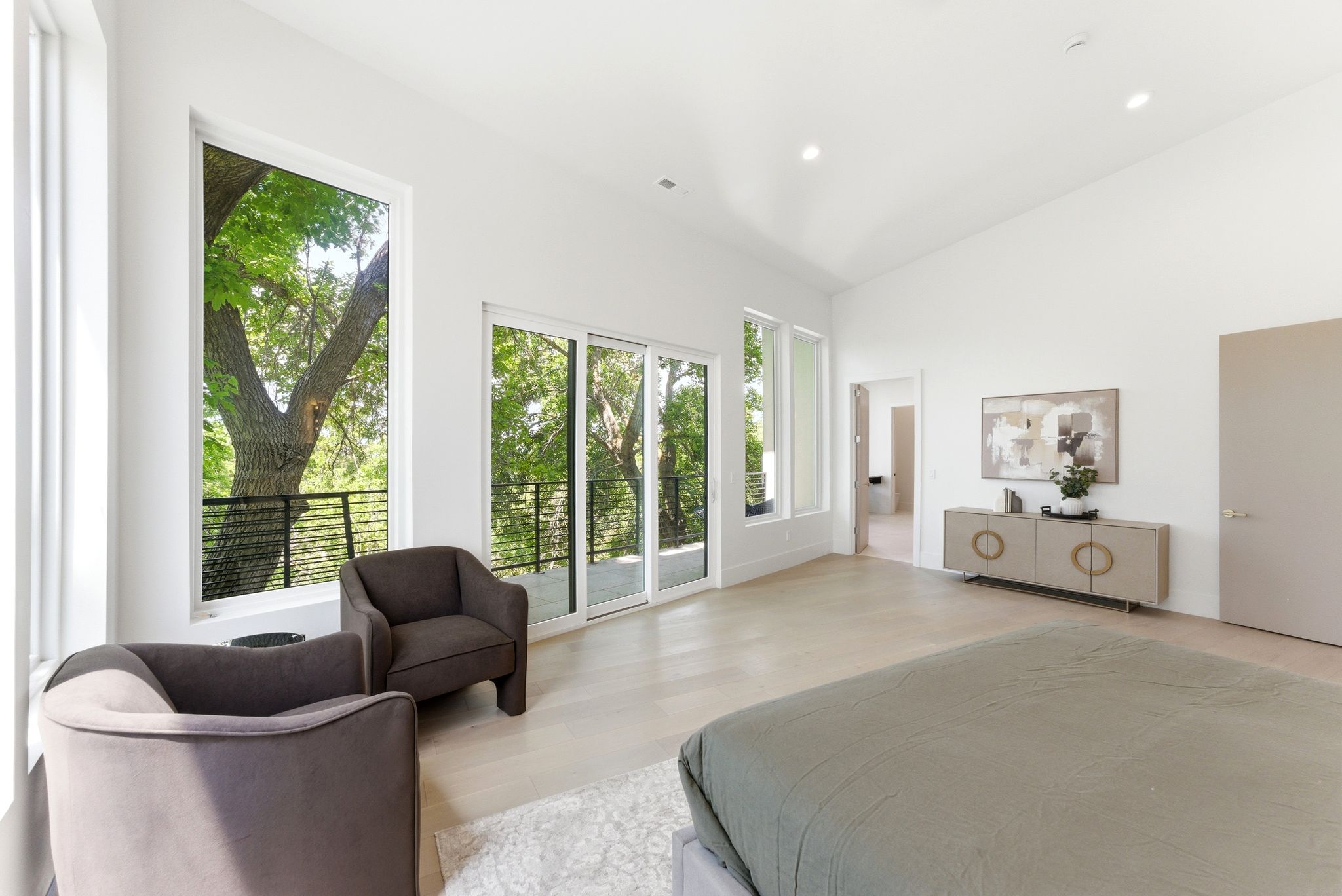 Spacious interior featuring expansive windows, sliding glass door balcony access, high vaulted ceilings, recessed lighting, and light wood-finish flooring