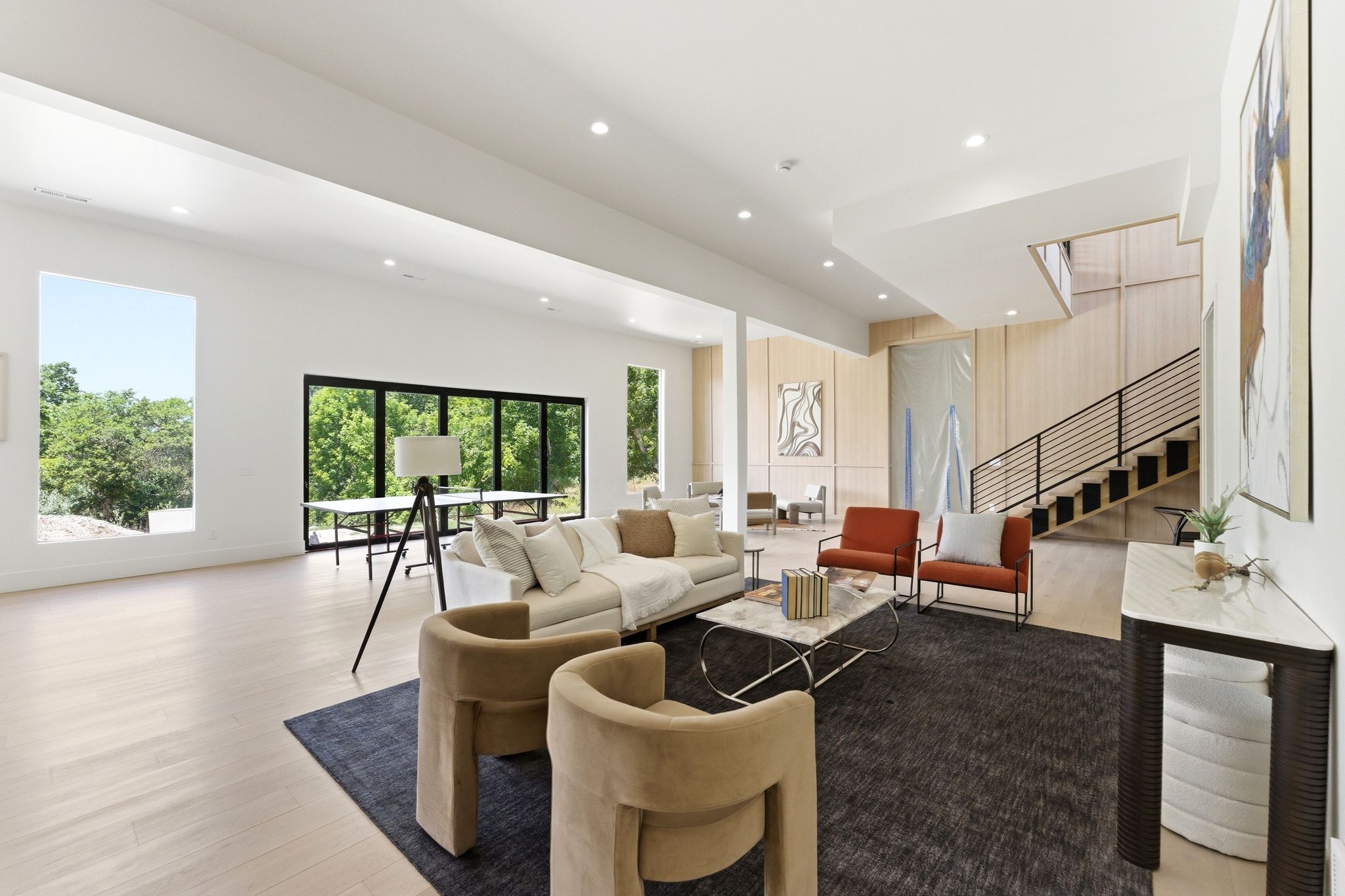 Spacious living area featuring light wood-finish flooring, recessed lighting, and large windows with black frames