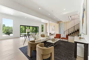 Spacious living area featuring light wood-finish flooring, recessed lighting, and large windows with black frames