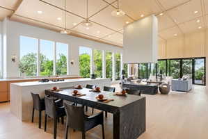 Open-concept living space featuring light wood-finish flooring, a wood-paneled vaulted ceiling, and a large central fireplace