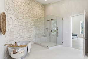 Spacious bathroom featuring a large stone accent wall and a freestanding soaking tub