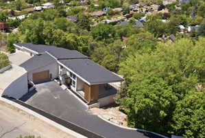 Contemporary architectural style with a dark shingle roof, extensive vertical window arrays, and a wood-finish garage door