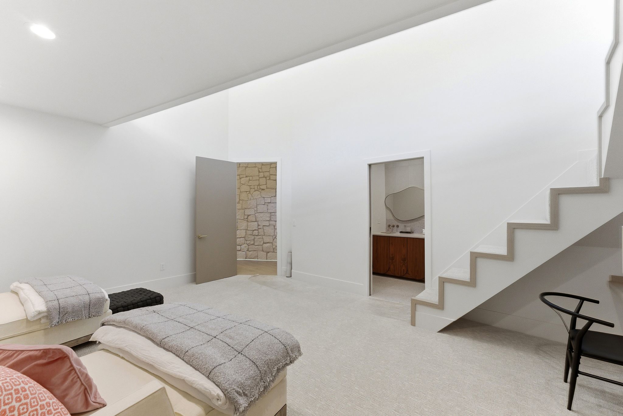 Open concept living space featuring a high ceiling, recessed lighting, carpet flooring, a floating staircase with light wood-finish treads, and a doorway leading to a room with stone walls