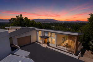 Modern architectural residence showcasing expansive window walls, an integrated garage, an outdoor balcony with slatted wood screening, and a prominent entry