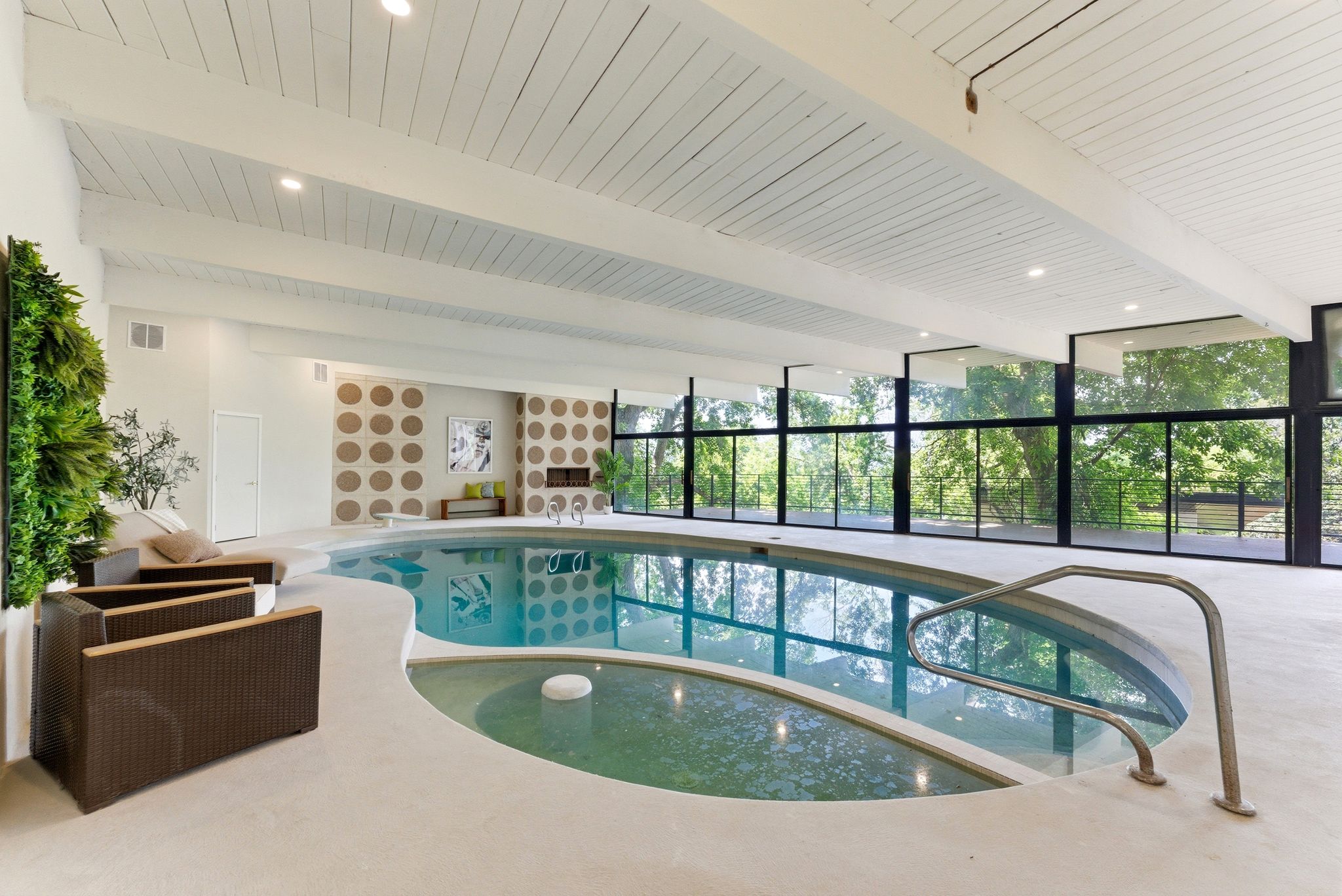 Indoor swimming pool featuring an integrated spa, expansive floor-to-ceiling windows, exposed beam ceiling, recessed lighting, and a decorative wall treatment
