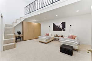 Loft-style room featuring high ceilings, a carpeted staircase, and a wood-finish built-in wardrobe