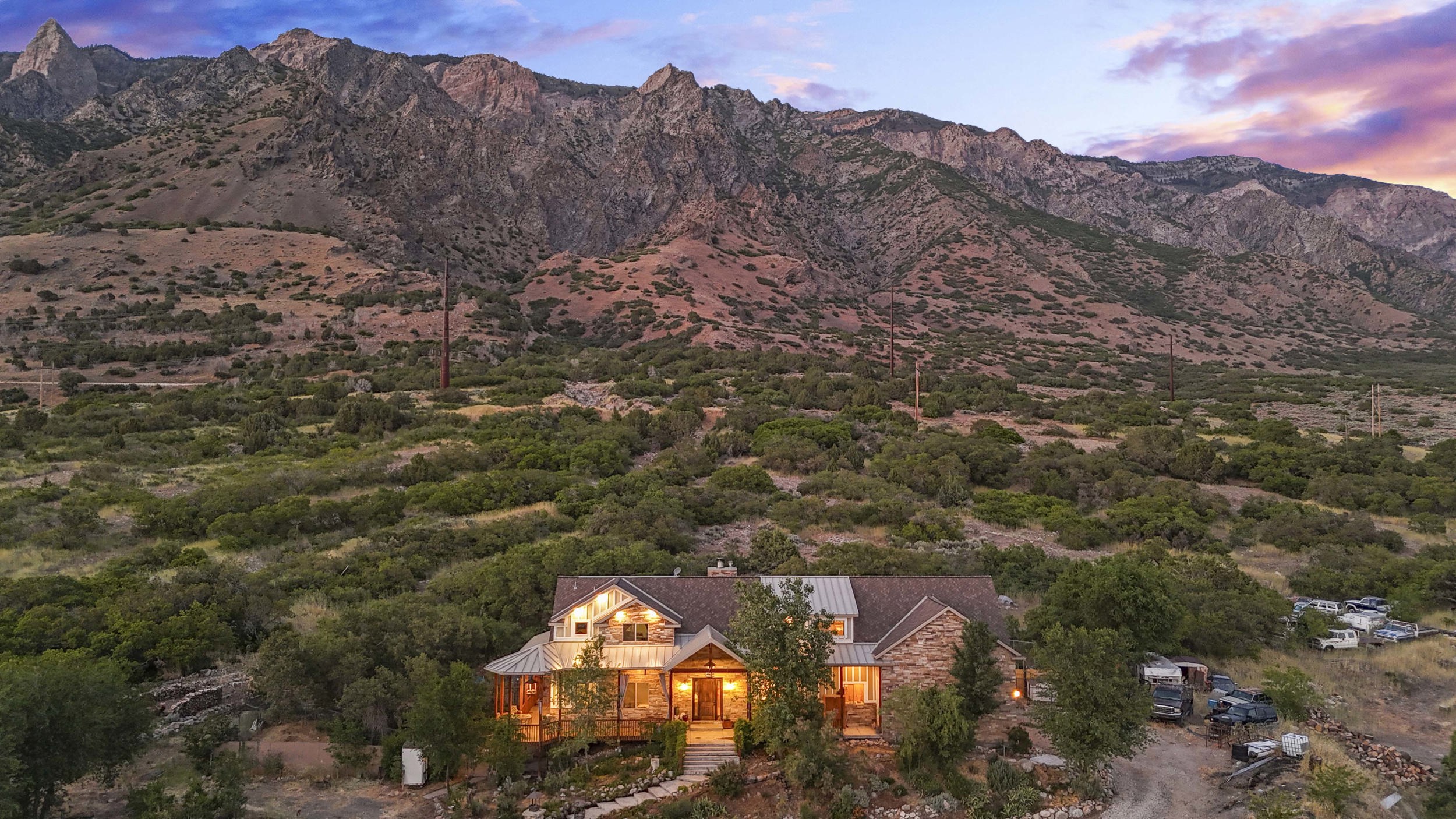 Stone and wood-sided residence featuring a multi-gabled roofline, covered porch, and exterior lighting