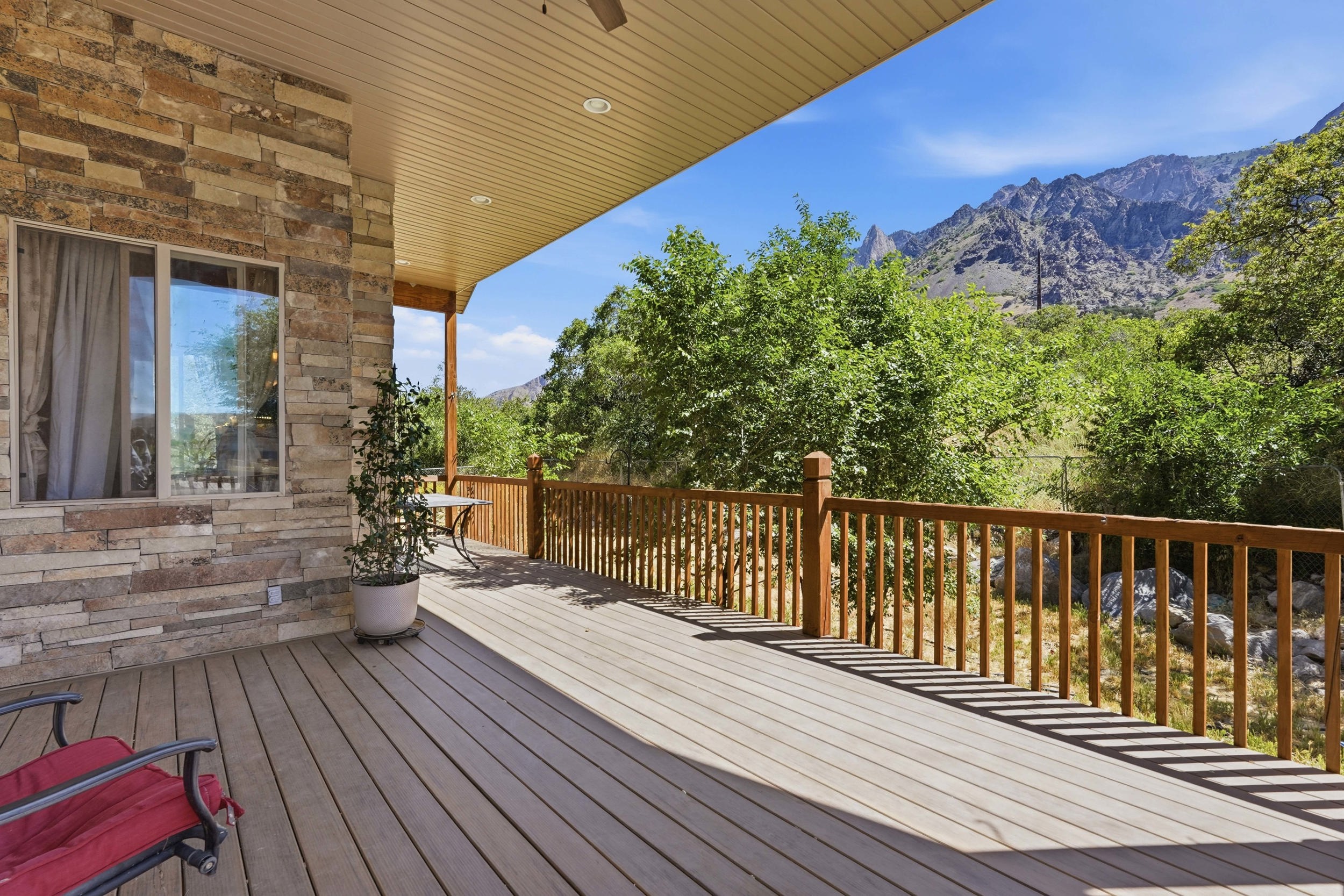 Expansive covered deck featuring wood-finish flooring, a wood railing, and a tongue-and-groove ceiling