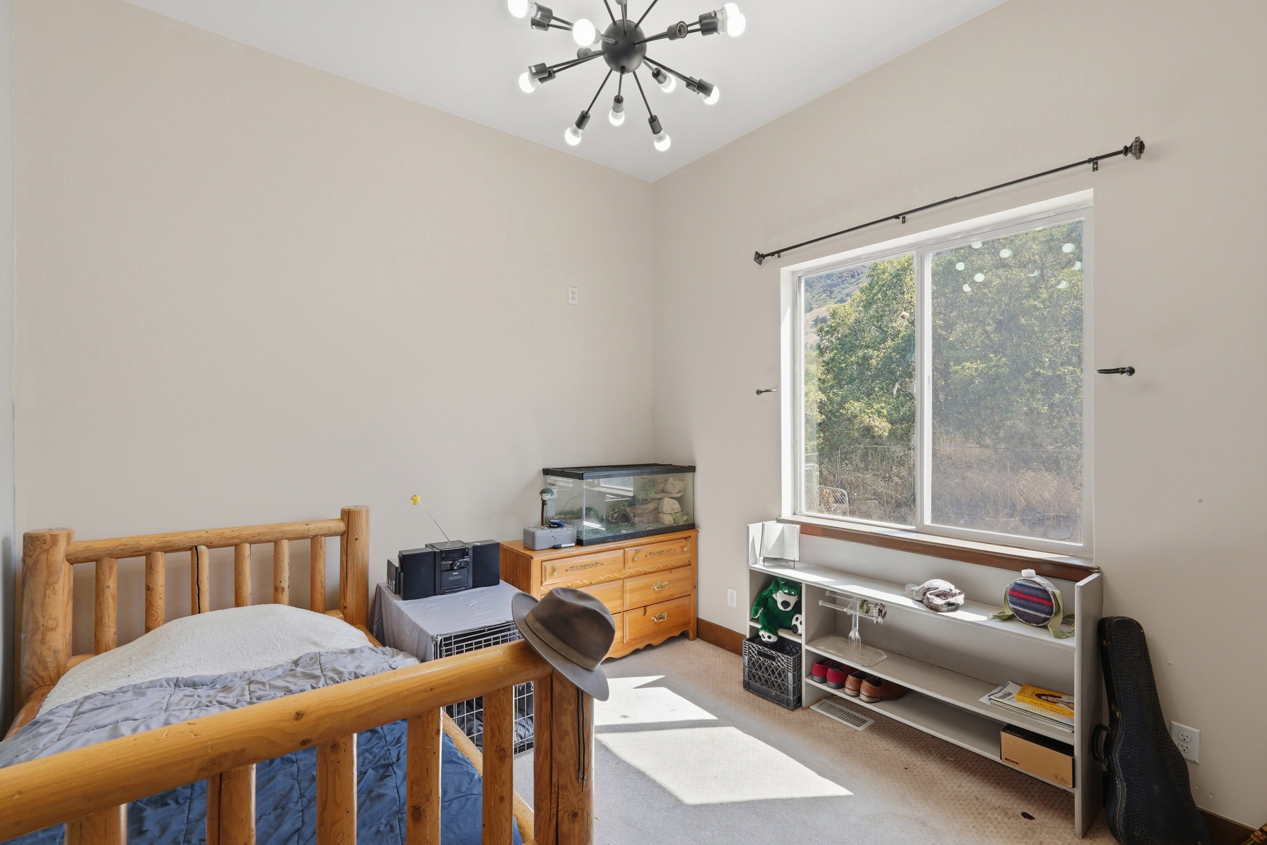 Bright room featuring a large window, a modern sputnik chandelier, light-colored walls, and carpeting