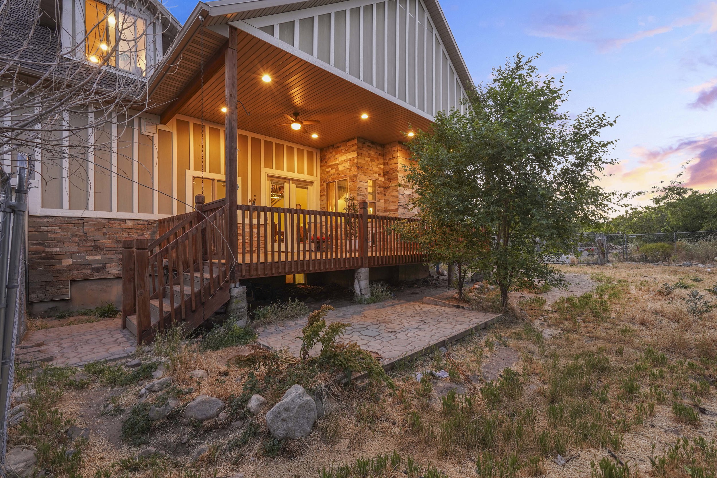 Covered wood-finish deck with recessed lighting and ceiling fan, accessed via double glass doors