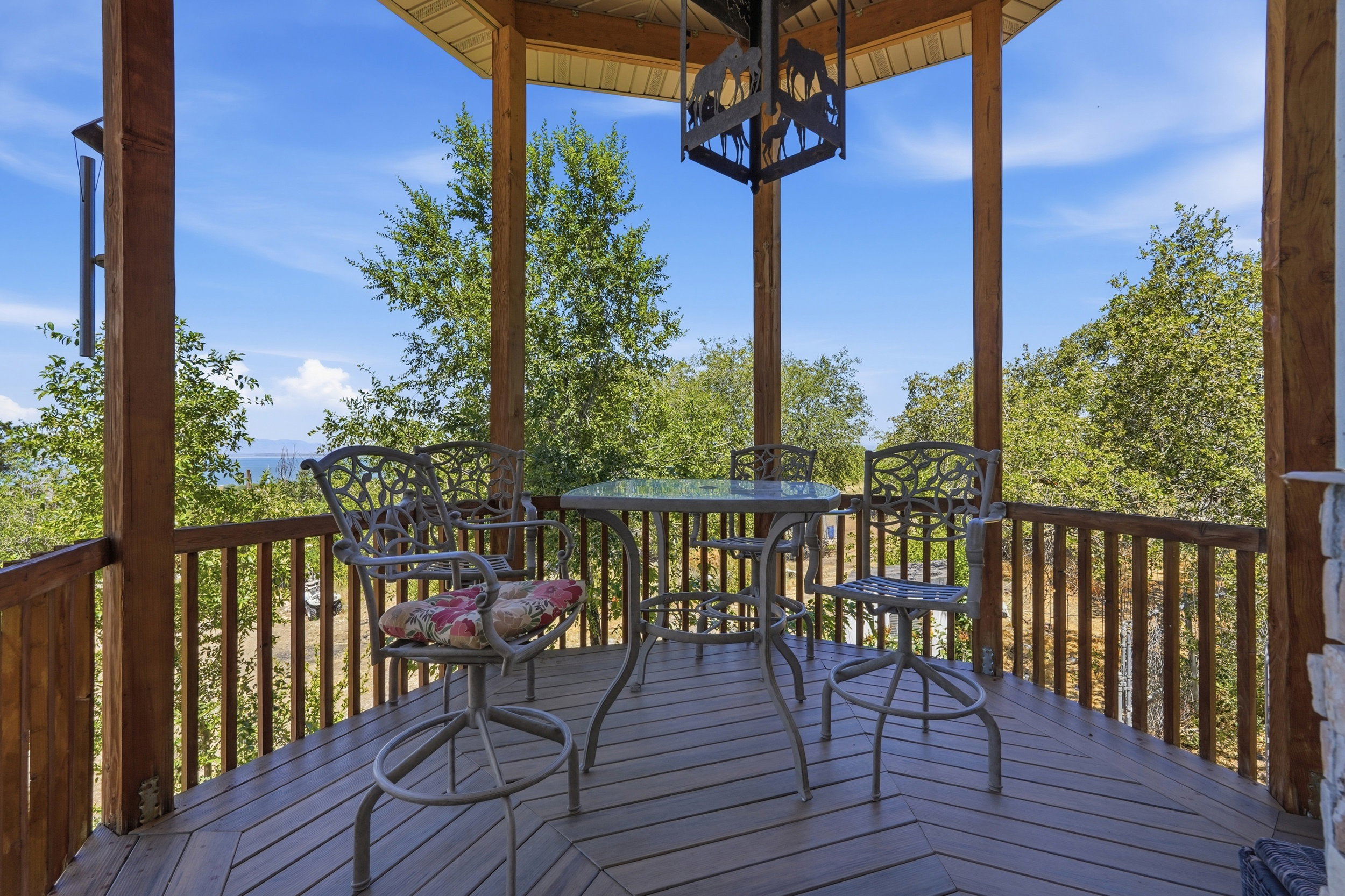 Expansive outdoor gazebo featuring wood-finish flooring, exposed wood beams, and a suspended decorative light fixture