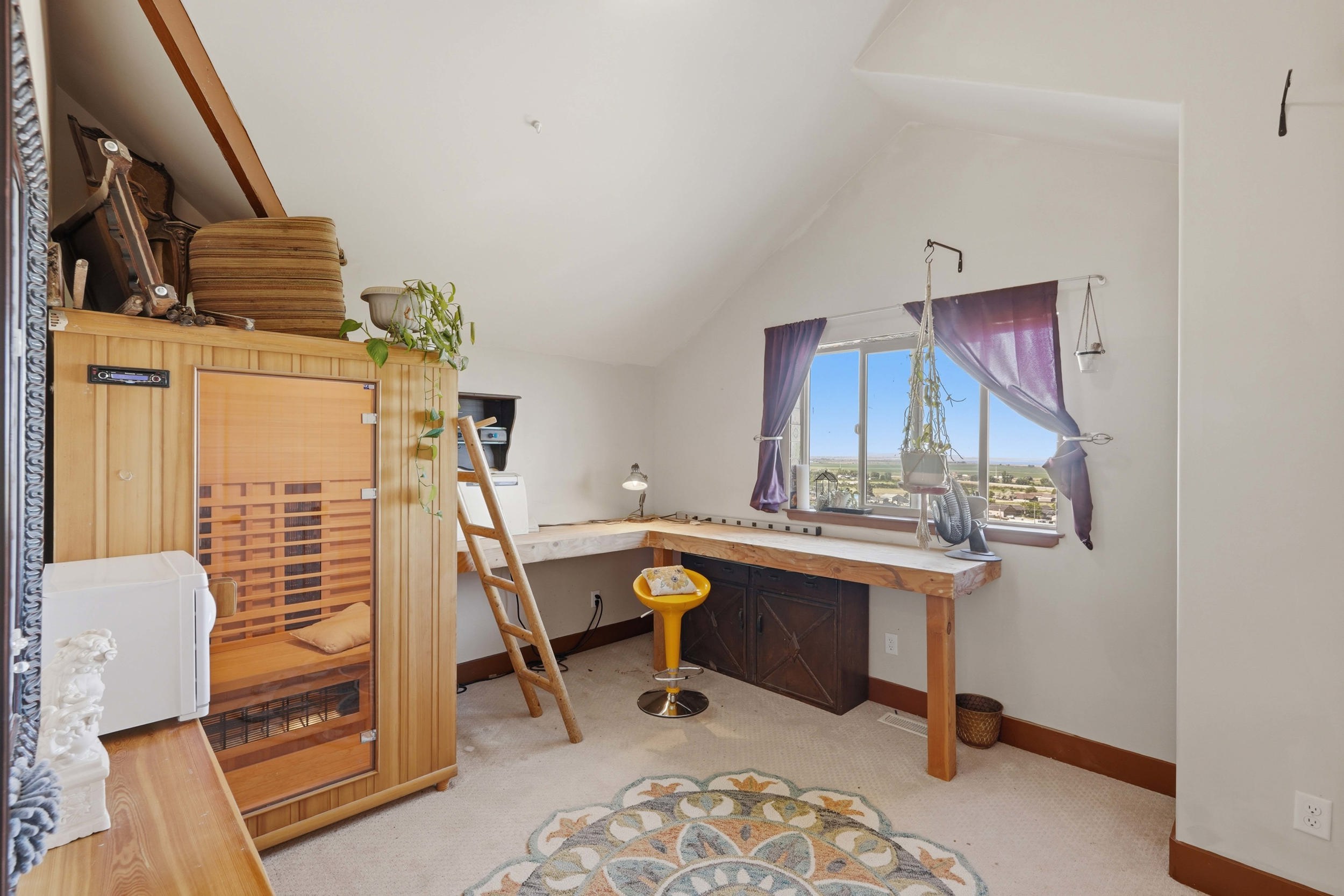 Attic space featuring a built-in sauna, L-shaped wood-finish desk with storage, and a large window
