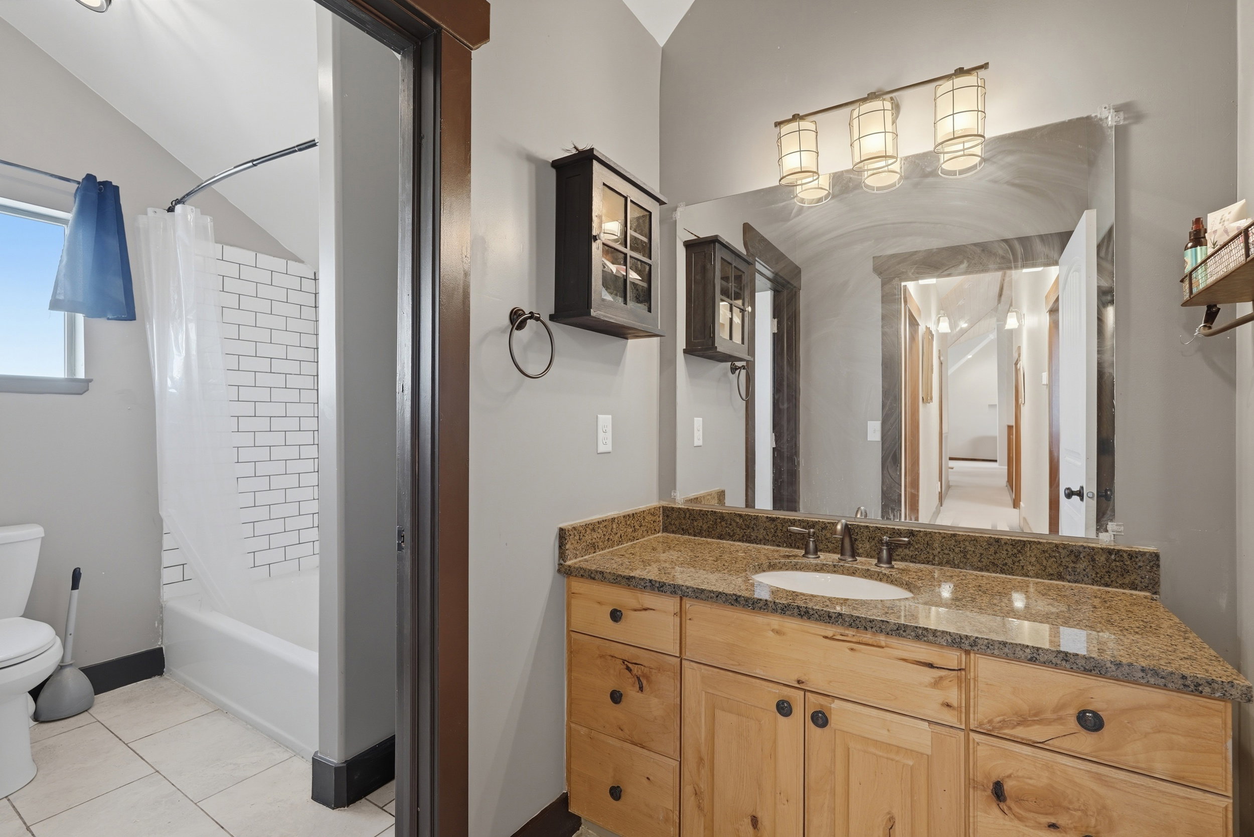 Bathroom vanity featuring light wood cabinetry, a granite countertop, and an undermount sink