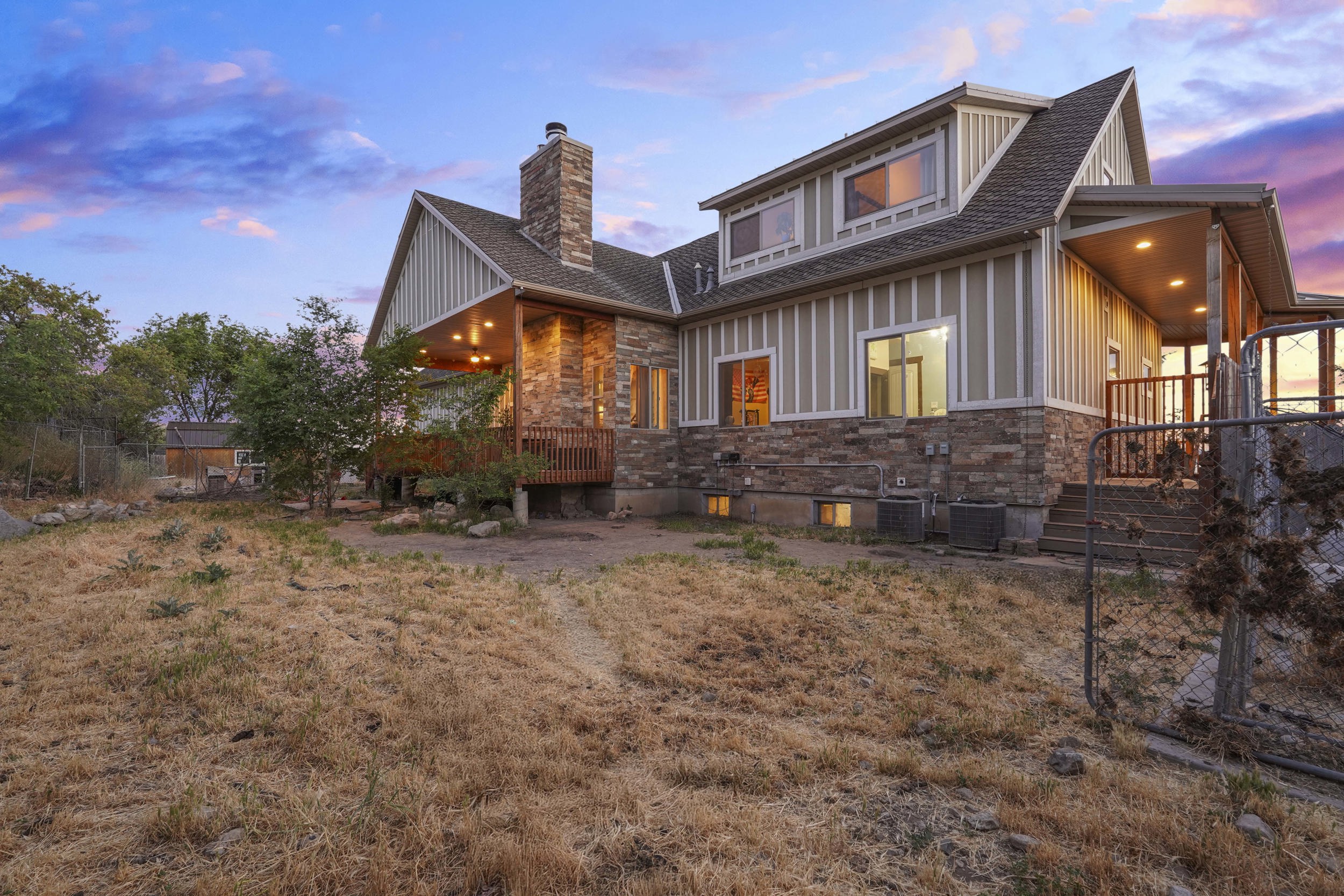 Multi-level property exterior featuring stone accents, vertical siding, and a prominent stone chimney