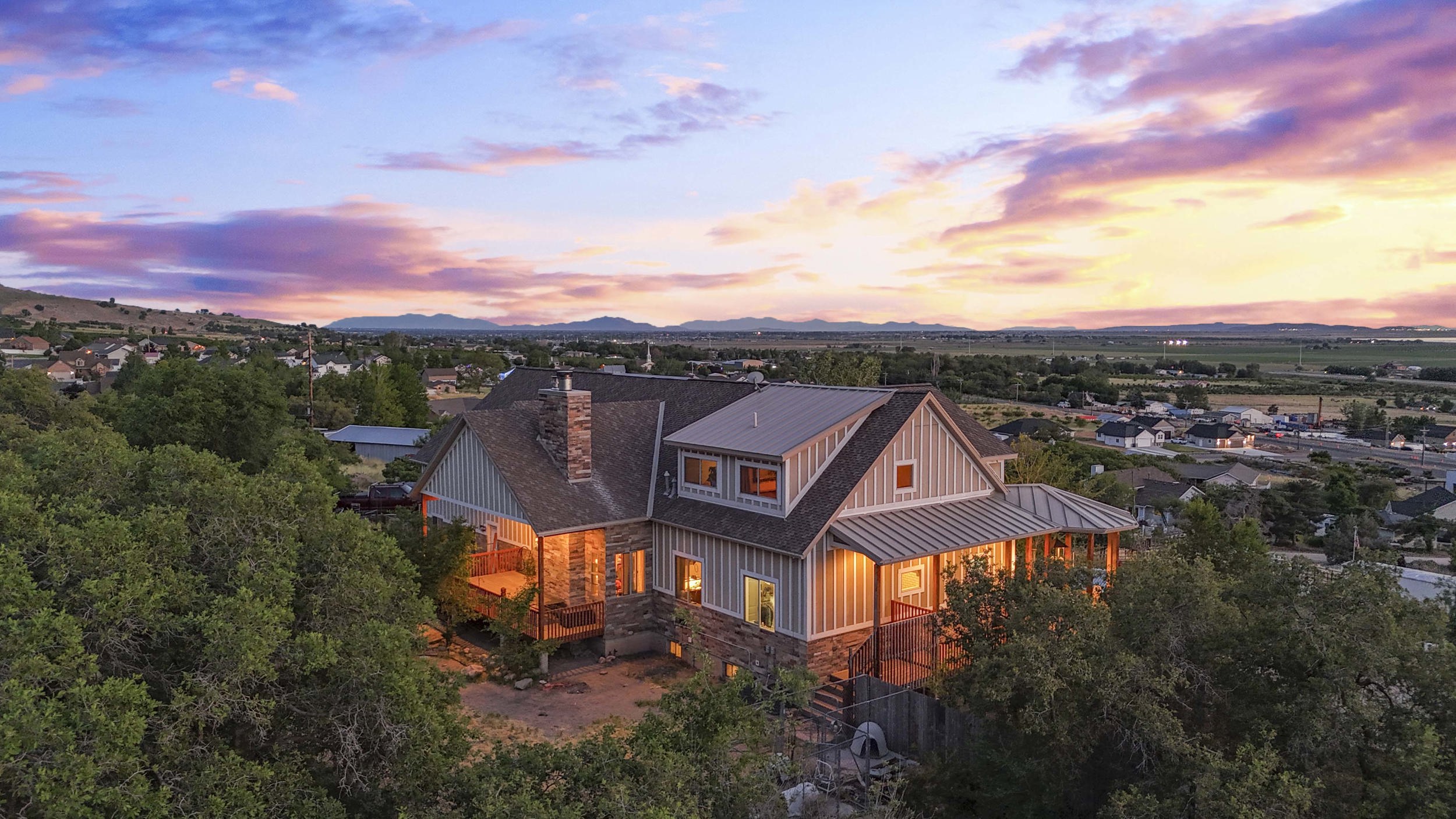 Hillside residence with stone and siding exterior, multiple dormer windows, and a covered porch