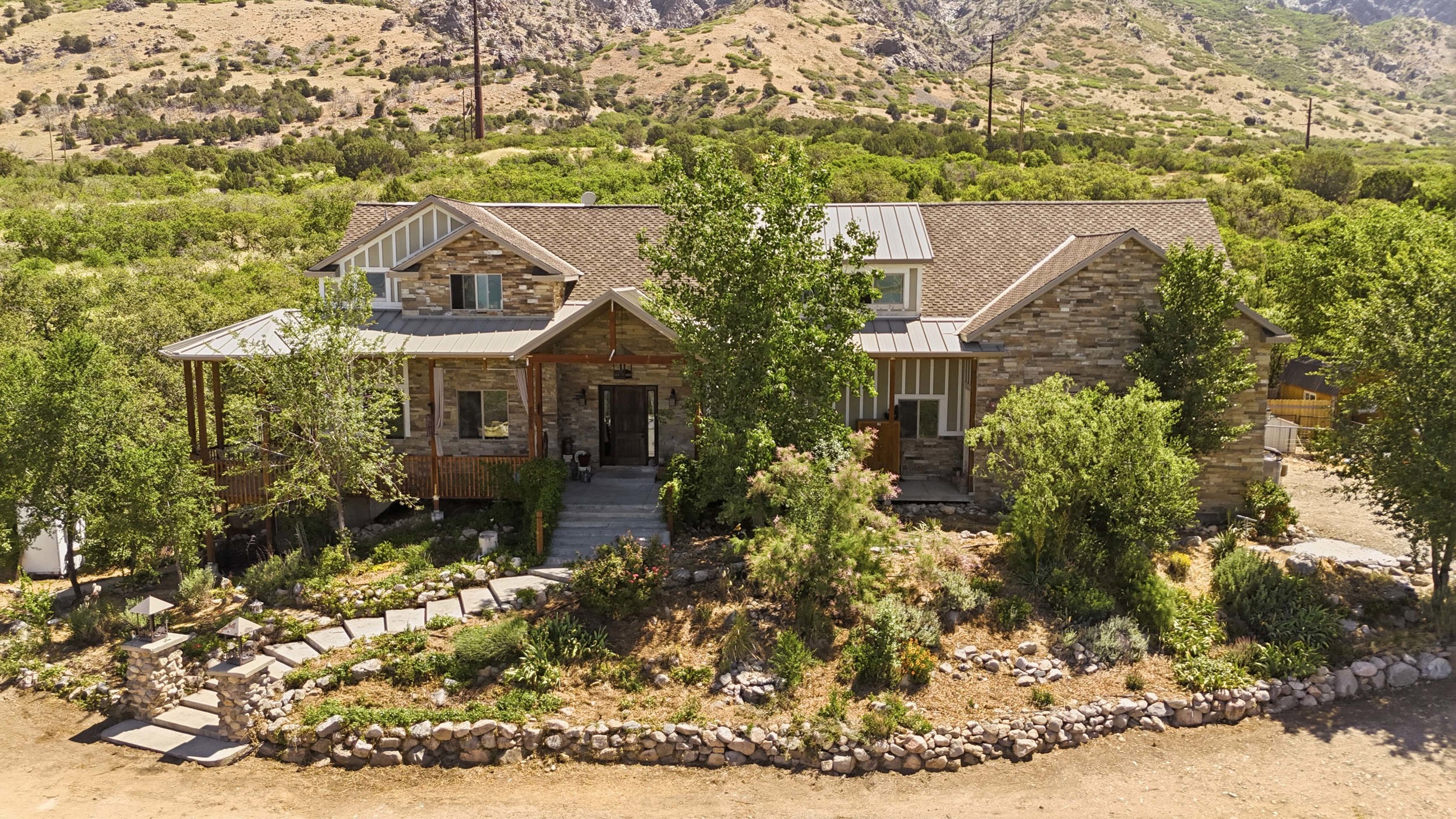 Stone-clad exterior featuring a prominent front entrance with a covered porch and exposed wood beams